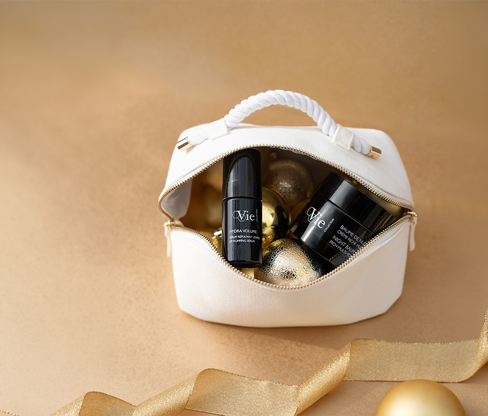 Night Balm Rich Multi-Youth Cream and Hydra Volume Lip Plumping Serum laying together in a white pouch.
