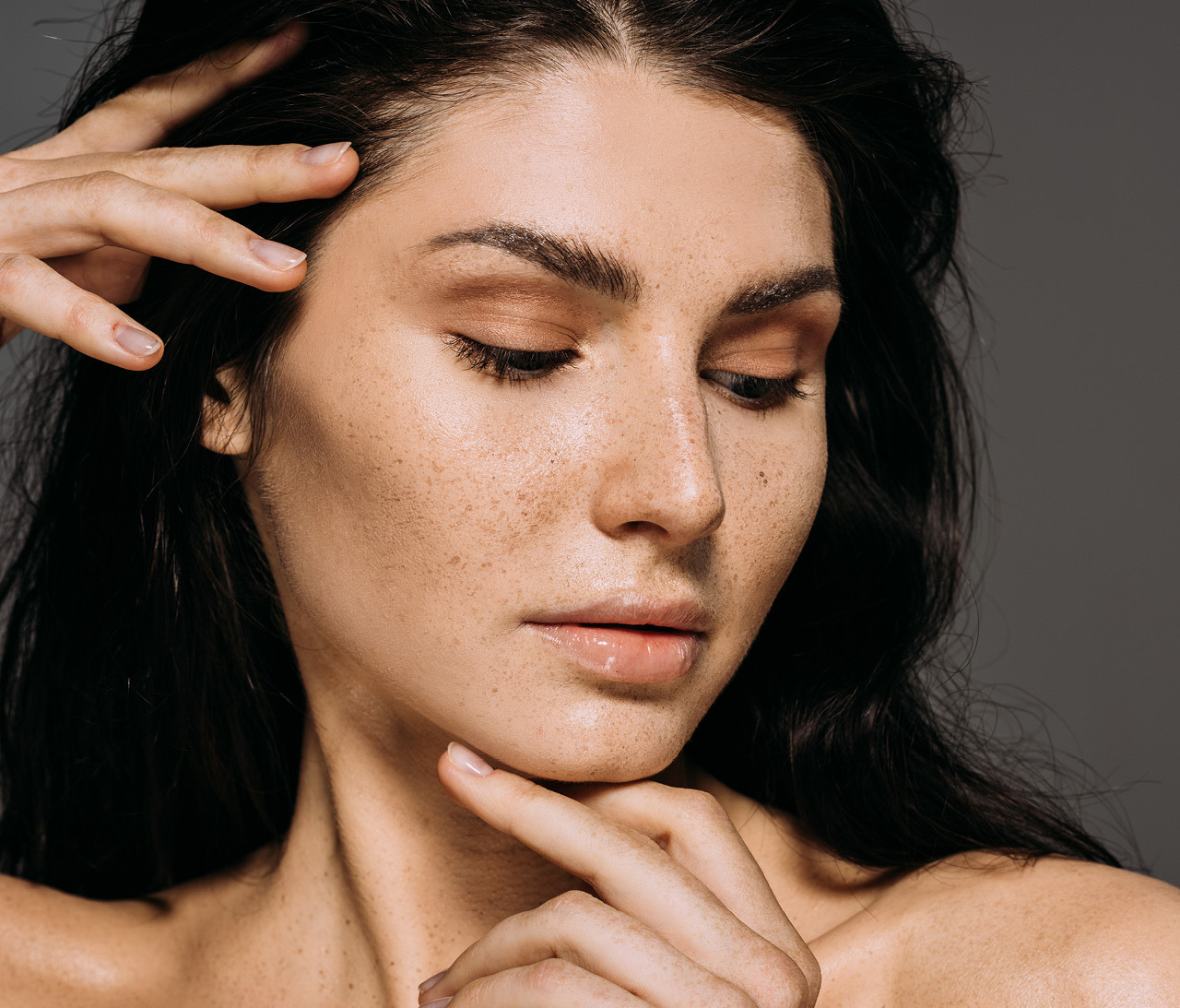 Woman gazing downward, gentle caressing her face