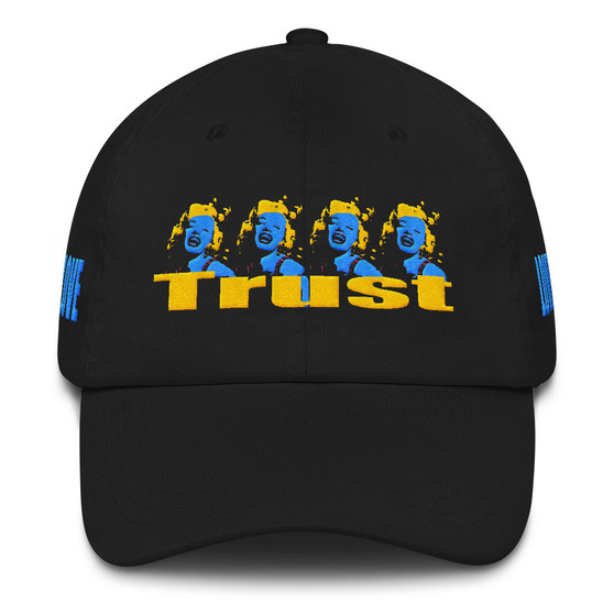 Black cotton dad hat with four blue-and-yellow Marilyn Monroe portraits and yellow TRUST lettering