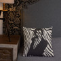Square zebra-print pillow with black female silhouette on gray quilted bedding and dark headboard.