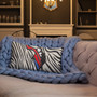 Napoleon zebra lumbar pillow with red sash accent on pink tufted sofa and blue chunky knit blanket.