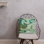 Teal and green Botticelli Girls portrait pillow on a black wire chair against a grey wall.