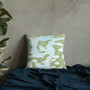 Sage green abstract camo Botticelli Girls pillow on navy textured fabric with plant accent.