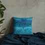 Cobalt and turquoise abstract textured Da Vinci Blue Bird pillow on navy blanket with plant accent.