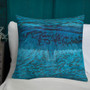 Turquoise and royal blue wave-print Da Vinci Blue Bird pillow on white chair against teal paneling.