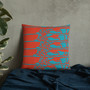 Vermilion orange pillow with five teal stylized figure rows on navy textured fabric by plant.