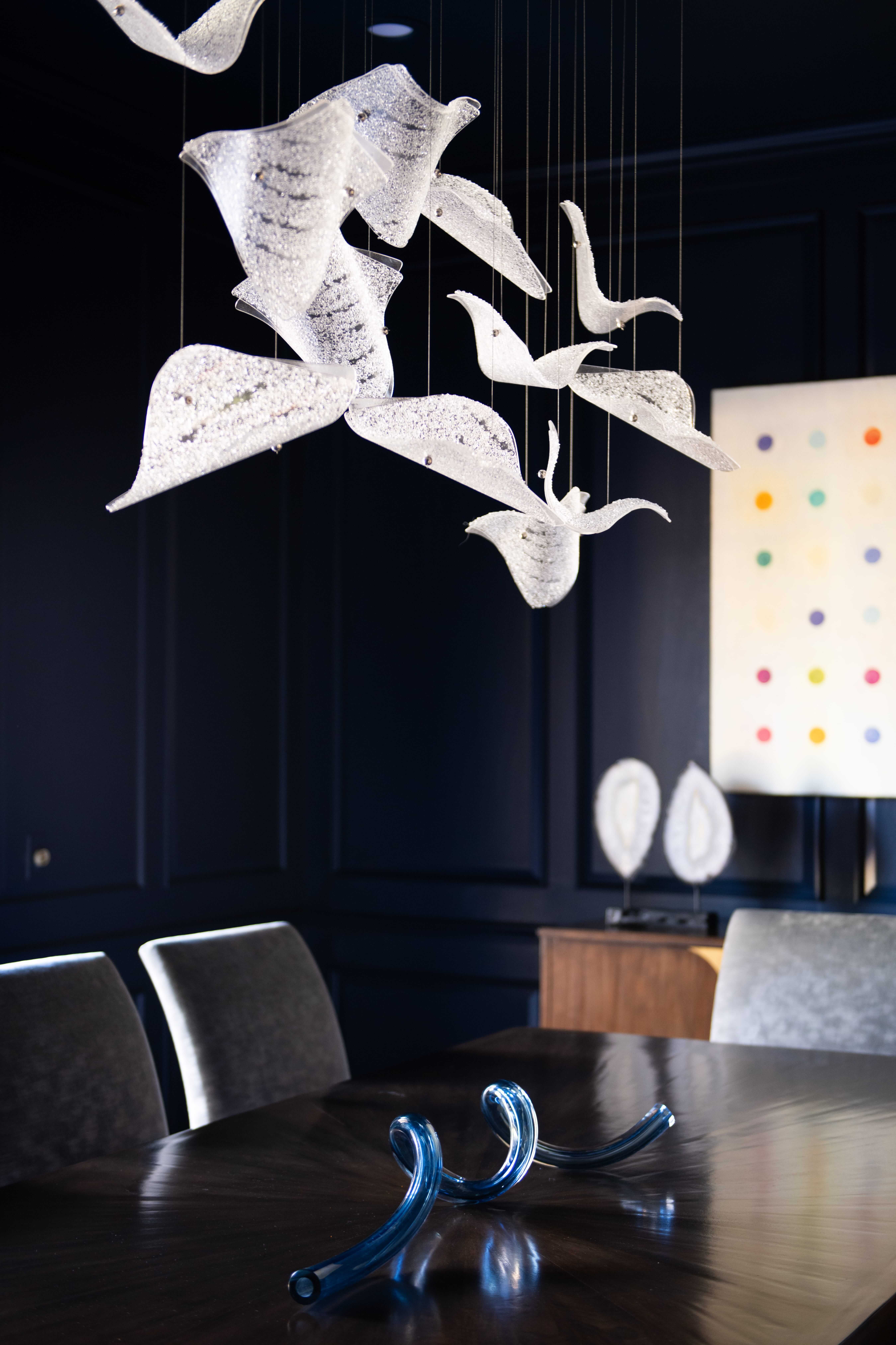 Sculptural luxury lighting design showcasing artisan craftsmanship, premium materials, and refined illumination accenting a modern luxury dining room with tailored furnishings, statement art, and architectural clarity.