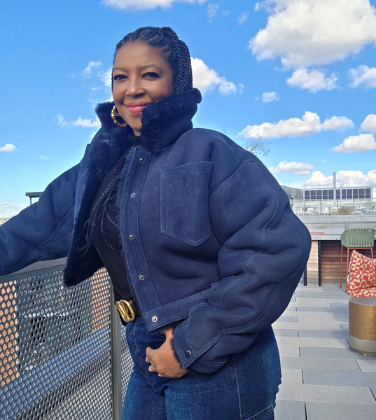 Model wearing navy blue short shearling sheepskin coat, side pose street style