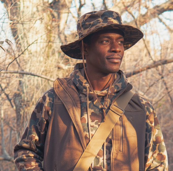 Man wearing Rothco Fred Bear camo boonie hat while hiking outdoors