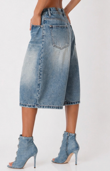Side view women’s long denim jorts with button-up detail, wide-leg culotte silhouette, and light blue faded wash.