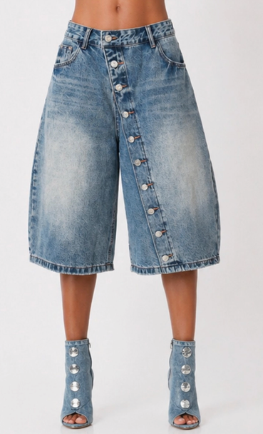 Front view of women’s long denim jorts with button-up detail, wide-leg culotte silhouette, and light blue faded wash.