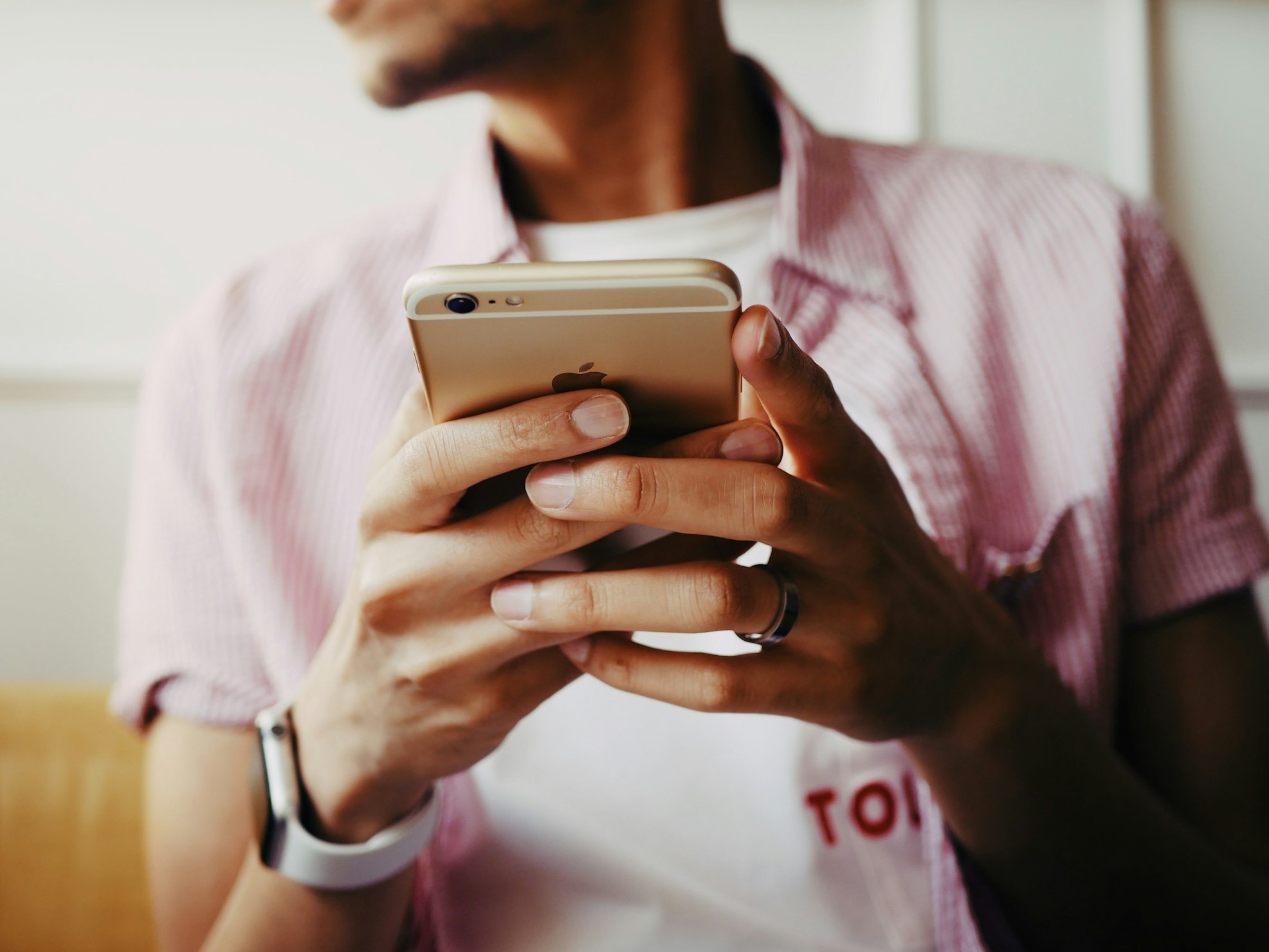 closeup of sitting man holding a gold iPhone