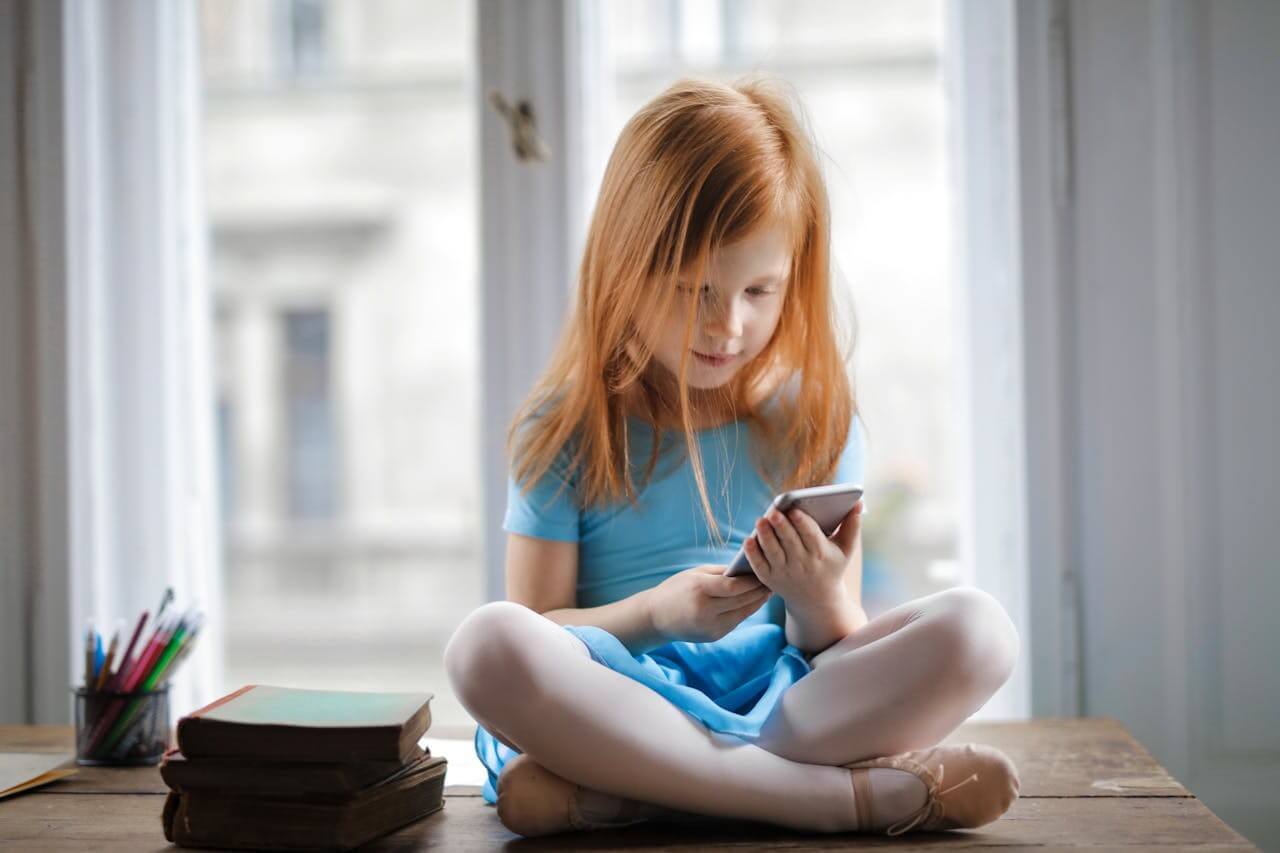 girl sitting on table and using smartphone