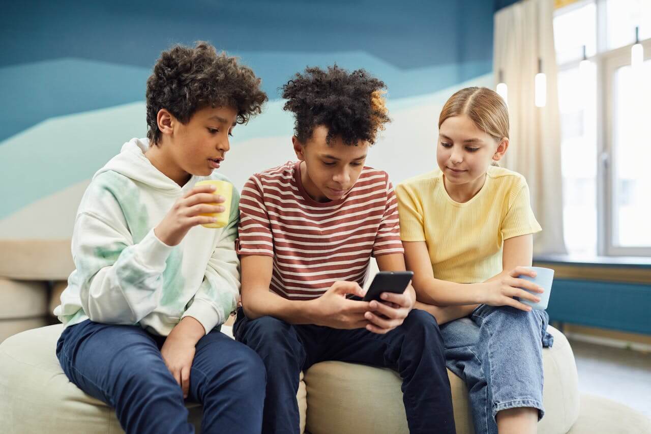  group of kids looking at smartphone in a painted room