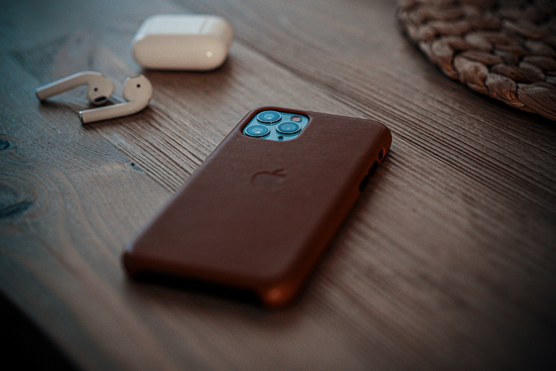an iPhone with a brown case on a wooden desk