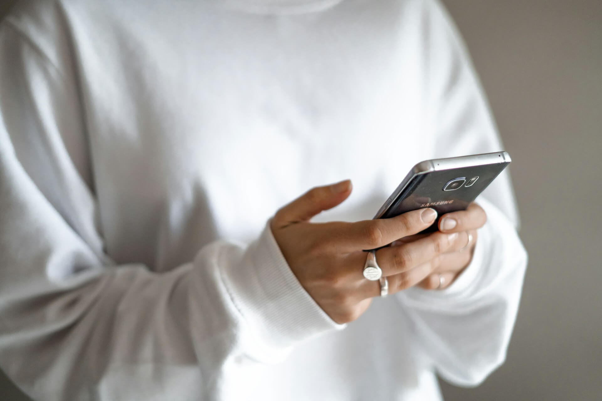 person in white long-sleeved shirt holding Samsung smartphone