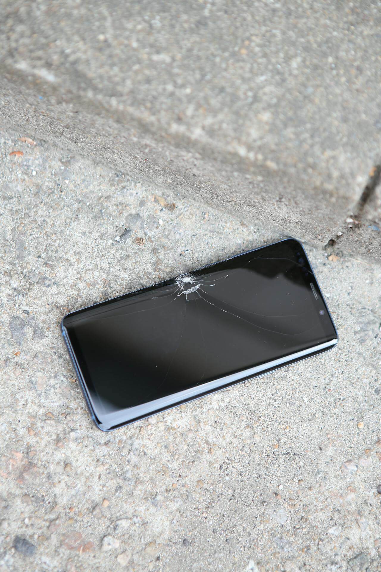 phone with a cracked screen on concrete floor