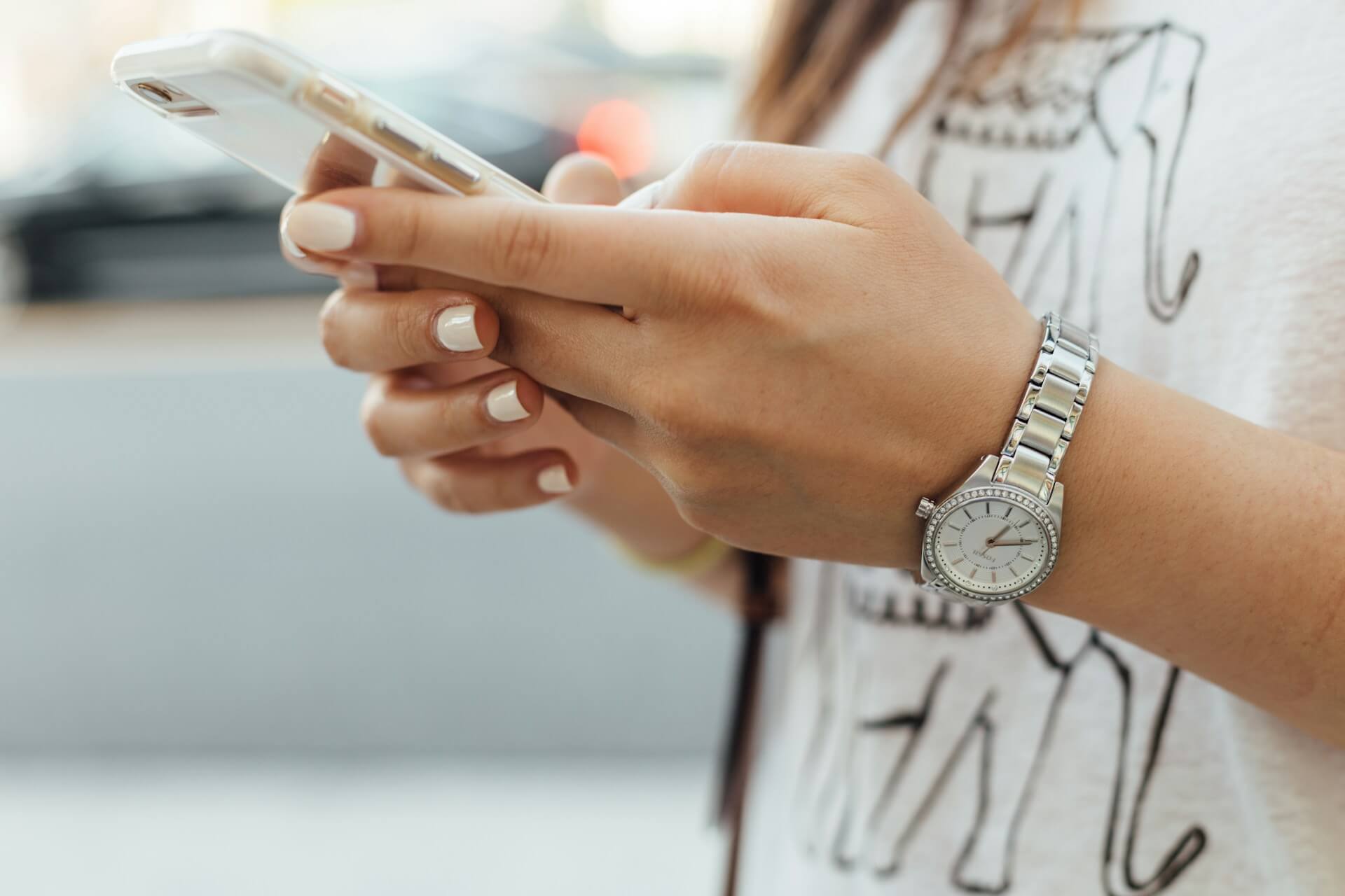 woman holding iPhone on the sidewalk