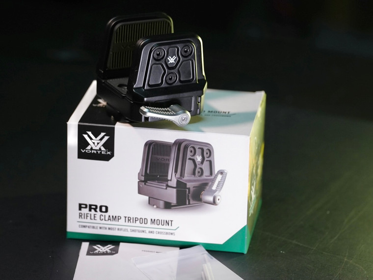 Close-up of Vortex rifle clamp with rubber jaws securing rifle handguard on tripod setup