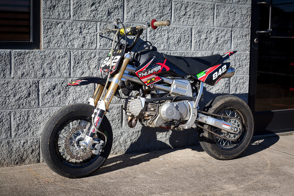 2013 Custom Super Moto Pit Bike modified by Marcos Ambrose Motorsport and Andrews Motorsports. This bike has a 187cc Thumper X engine, high compression electric start, Performance Shox suspension, custom stainless steel exhaust, Kehin 28mm carburetor and soft compound race tires. This bike has a mixture of components on it including Braap, Piranha, and YCF.