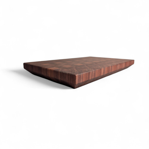 alt="Angled view of a modern Black American Walnut end-grain cutting board featuring a 45-degree chamfered bottom edge that creates a floating effect."