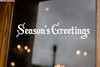 Season's Greetings Christmas vinyl decal in decorative Old English Gothic lettering displayed on glass window for holiday decorating