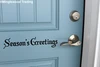 Season's Greetings Christmas vinyl decal in decorative Old English Gothic lettering displayed on glass window for holiday decorating