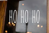 Ho Ho Ho Christmas vinyl decal featuring tall skinny farmhouse style lettering arranged horizontally on a glass window