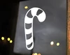 Striped candy cane Christmas vinyl decal displayed on a glass window featuring a curved hook and diagonal candy stripe cutouts