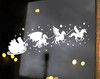 White Christmas vinyl window decal featuring Santa Claus in a gift-filled sleigh pulled by a winged dragon, griffin and winged unicorn surrounded by stars and sparkling shapes