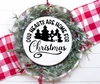 Our Hearts Are Home for Christmas vinyl window decal featuring evergreen pine trees, a small house, heart accents, arched lettering and decorative Christmas script