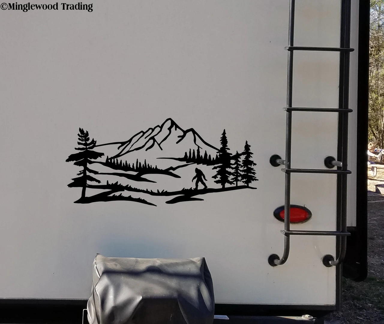 Bigfoot Sasquatch mountain landscape vinyl decal V2 featuring walking cryptid silhouette, mountain peaks, evergreen forest and pine trees for RV campers and travel trailers