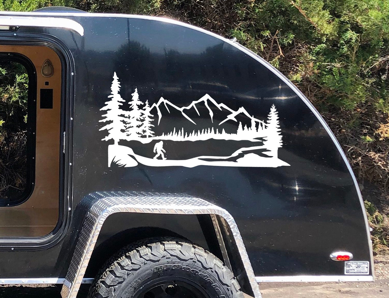 Bigfoot Sasquatch walking through mountain forest landscape with pine trees scenic vinyl decal for RV camper travel trailer and motorhome