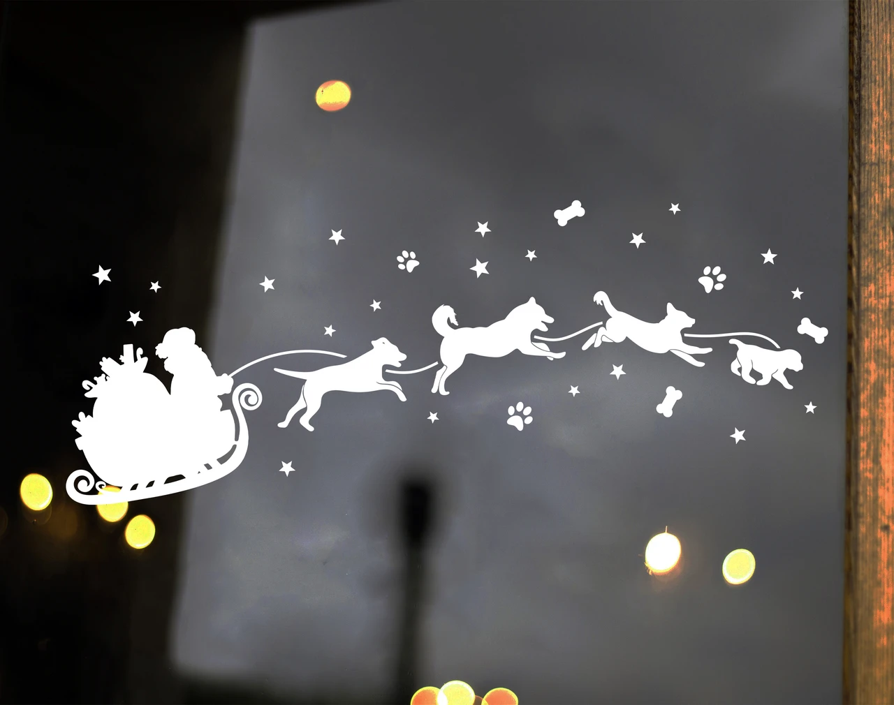  Christmas vinyl decal of Santa Claus in a sleigh pulled by running dogs with stars, paw prints and dog bones on a glass window
