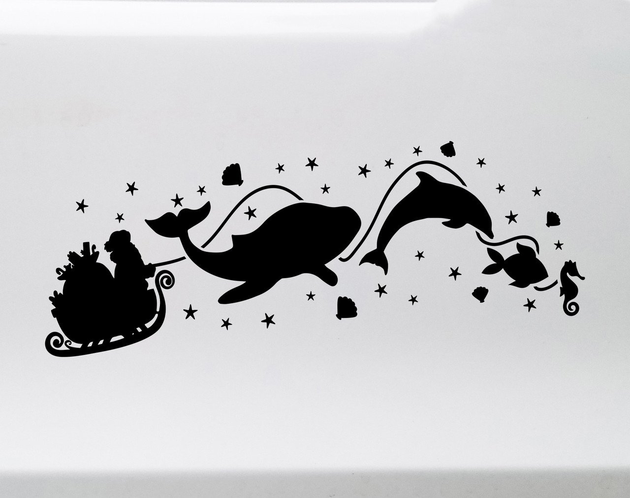 White Christmas vinyl window decal featuring Santa Claus in a sleigh pulled by a whale, dolphin, fish and seahorse surrounded by stars and seashells