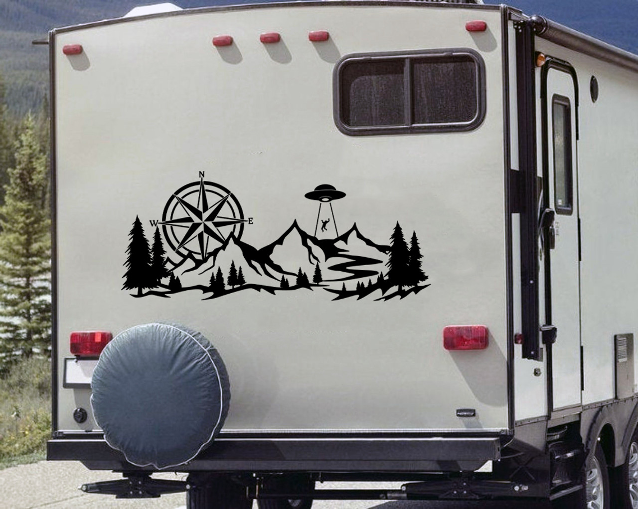 Back of Camper RV with a large black vinyl decal featuring a compass, and an alien spaceship abducting a man over a mountain forest scene