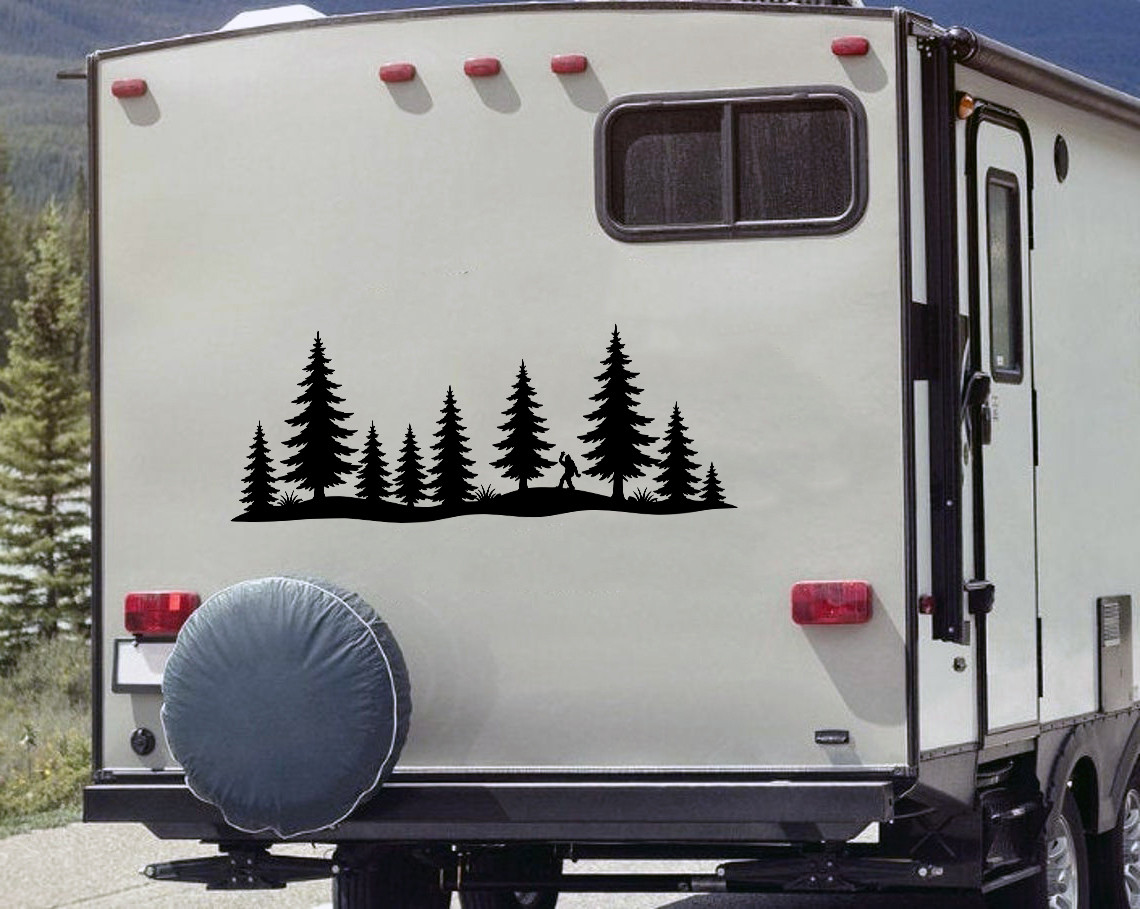 bigfoot sasquatch waving vinyl sticker decal with pine forest silhouette applied to rv camper rear window outdoors scene