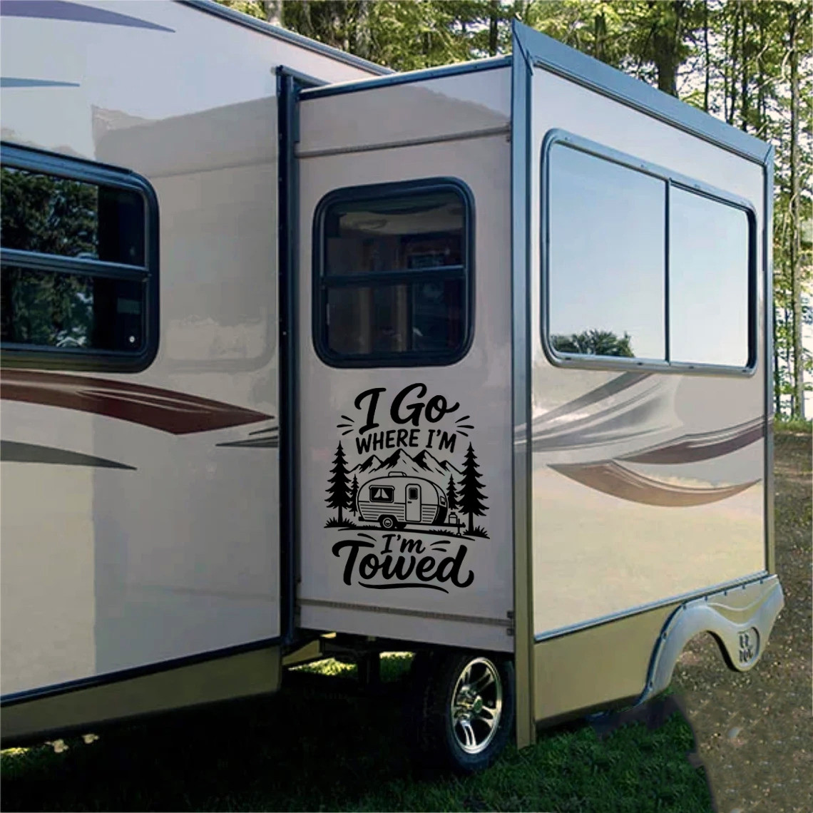 I Go Where I'm Towed vinyl decal featuring a travel trailer, mountains and pine trees displayed on a camper exterior