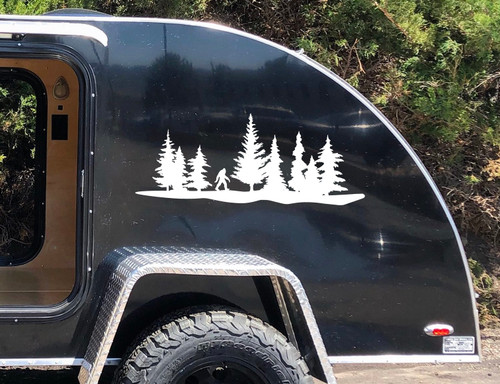 Bigfoot Sasquatch walking through pine forest tree line vinyl decal featuring evergreen trees and woodland landscape on RV camper storage compartment door