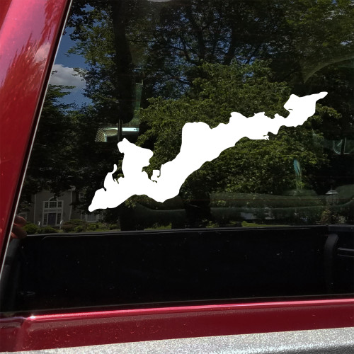 White Fishers Island New York geographic shoreline outline vinyl decal applied to the dark rear window of a red SUV, showing the island's elongated coastal silhouette