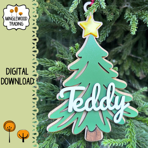 Personalized 5 inch layered MDF Christmas tree ornament featuring a green evergreen tree with yellow star topper and raised white custom name lettering on a natural wood-look backing with ribbon hanger.