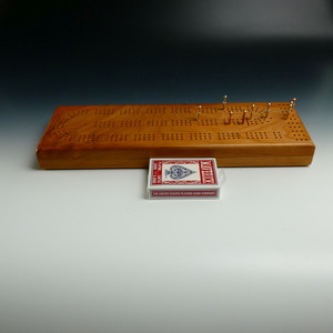 Cherry 3 Player Cribbage Board with pegs in different holes and a pack of playing cards in front.