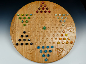 A Chinese checkers board in oak with celtic designs between the points, marbles, and a die.