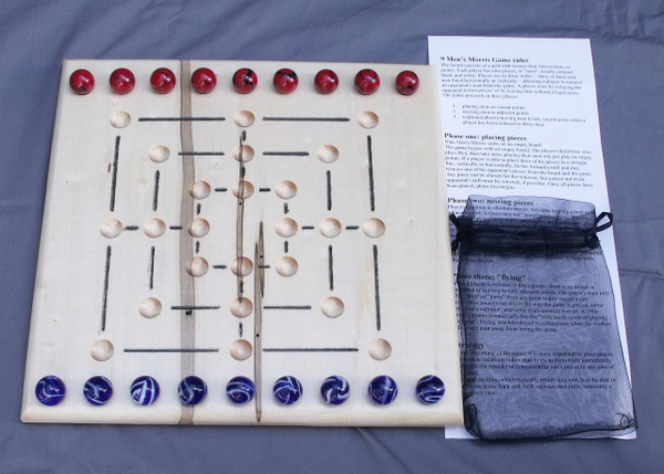 A Nine Man Morris Game with the marbles in their starting position, the instructions, and the storage bag.