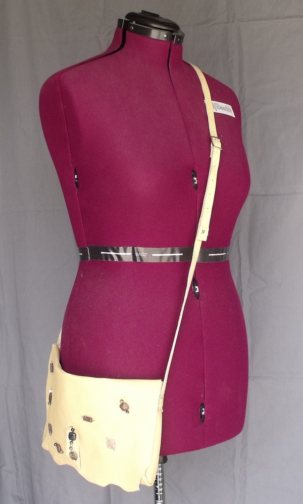 The crossbody purse on a dressmaker's mannequin showing where the purse would fall on the average person.