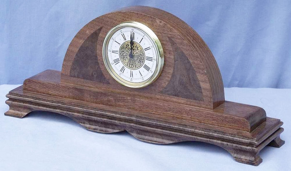 Side angle of a solid walnut fireplace mantle clock highlighting the deep 4-inch rich wood base profile.
