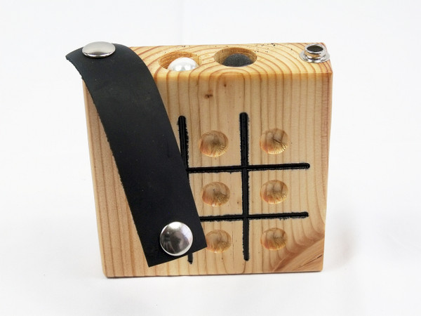 The Tic Tac Toe game with the leather strap unsnapped on one side showing the marbles in the storage compartment.