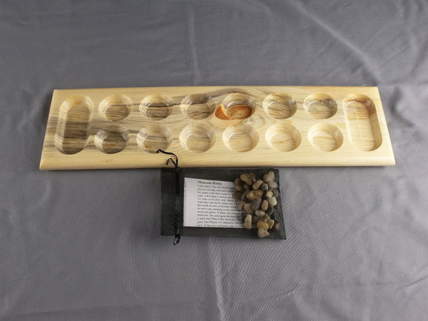 Mancala game in Beetle Kill Pine with the stones and rules in the storage bag.