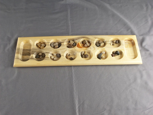 Mancala game in Beetle Kill Pine with the stones in their starting positions.
