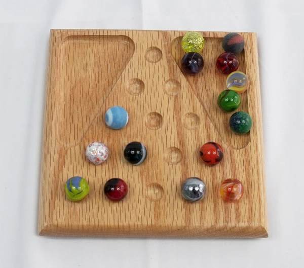 A small marble solitaire game in oak in the middle of a game.